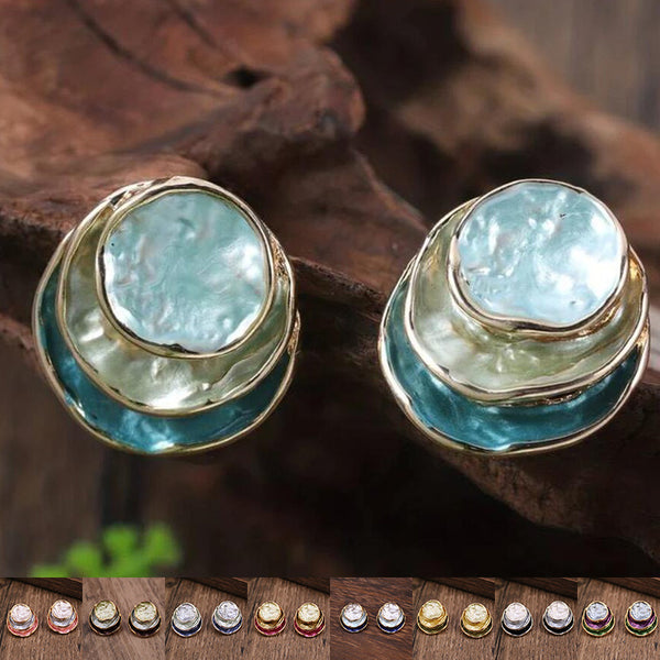 Pair of earrings with turquoise stones and gold accents on a wooden surface.