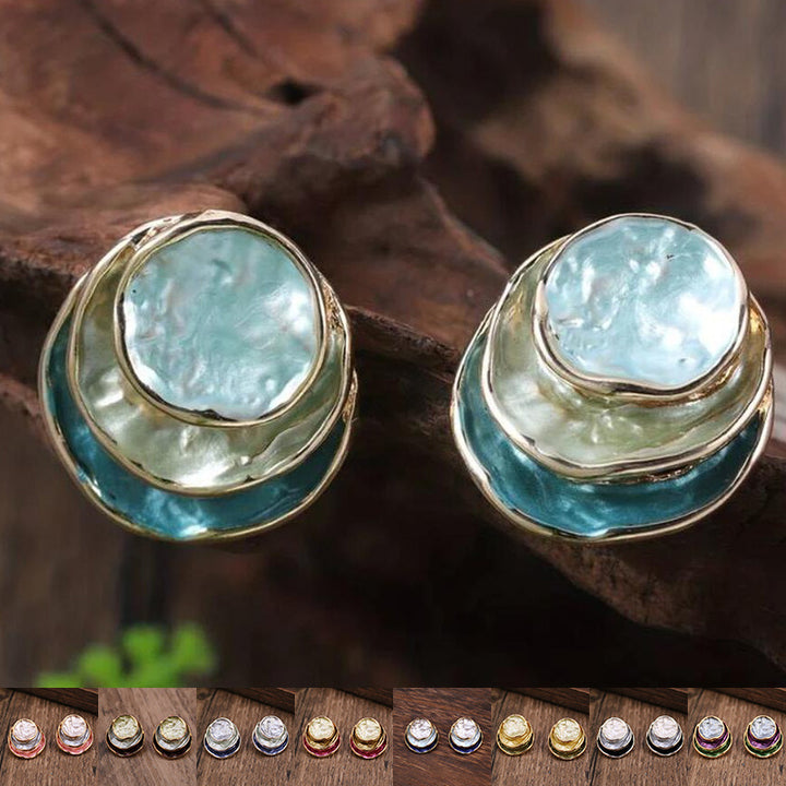 Pair of earrings with turquoise stones and gold accents on a wooden surface.