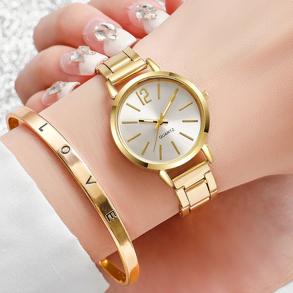 Gold wristwatch and bracelet on a wrist with a light background
