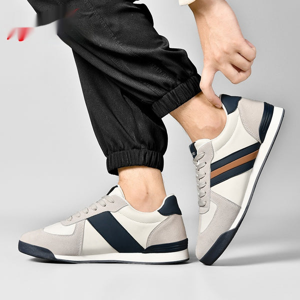 Person wearing gray sneakers with navy and brown accents on a light gray background