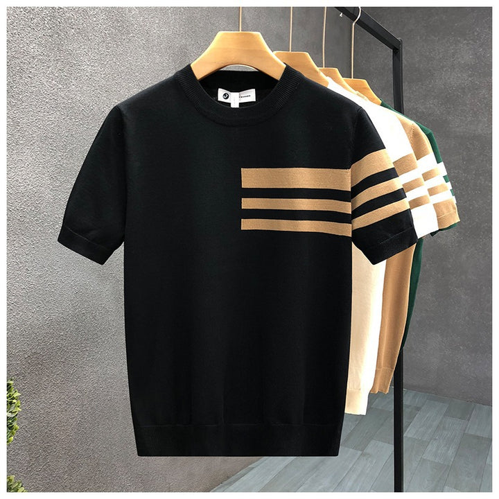 Black t-shirt with beige stripes on a hanger against a gray wall.